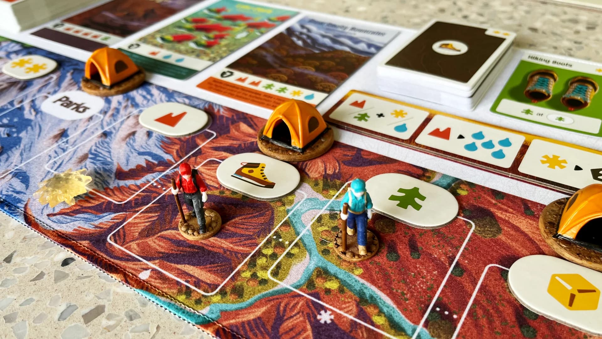 A colourful board game in play with miniature hikers and tents